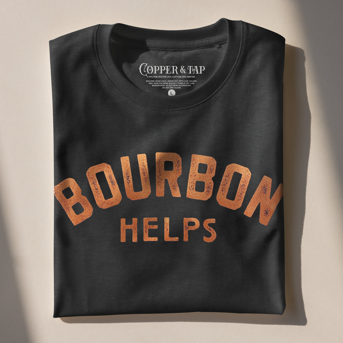 Black t-shirt folded neatly with 'Bourbon Helps' text on a beige background