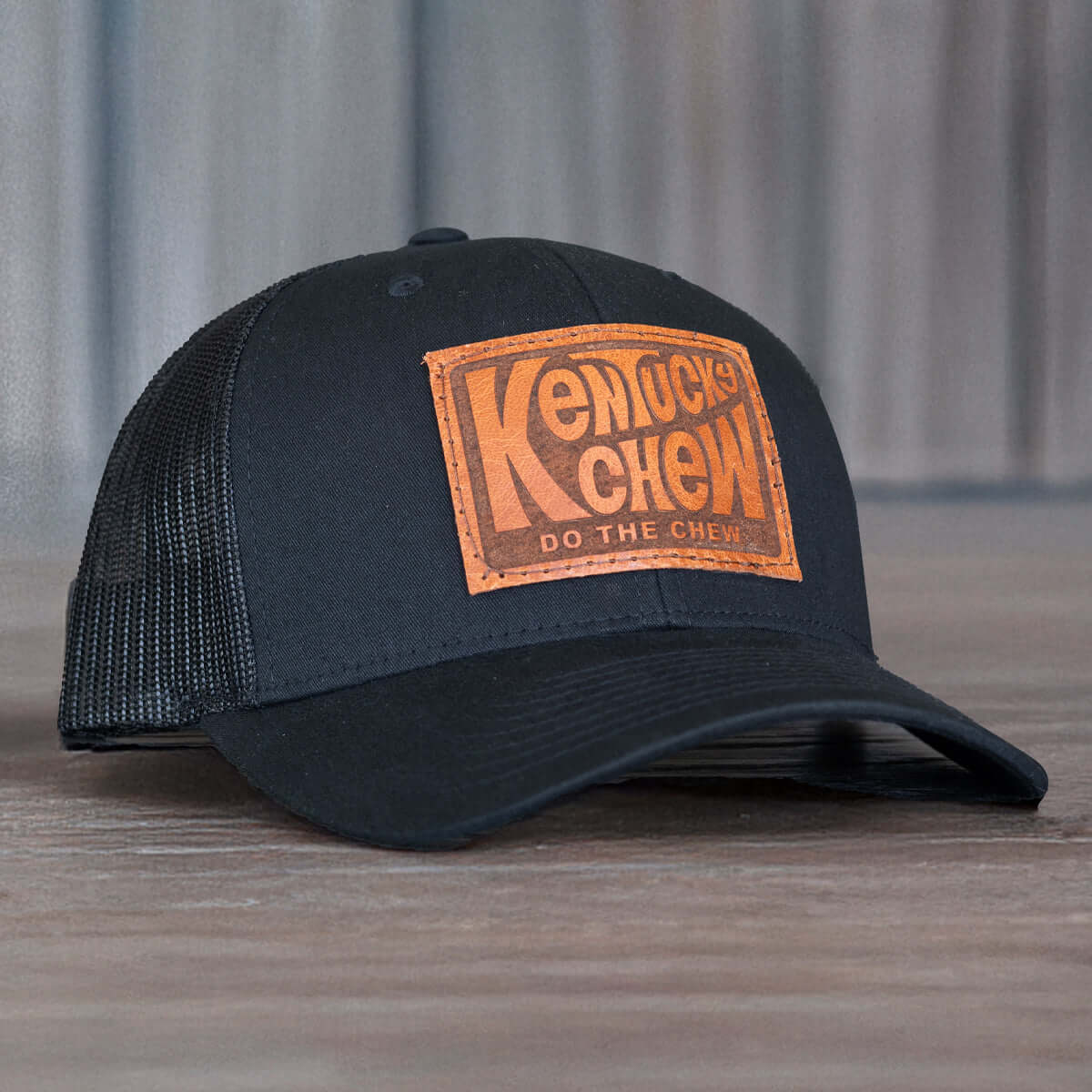 Kentucky Chew whiskey hat, black trucker snapback with leather engraved patch, great for bourbon enthusiasts.