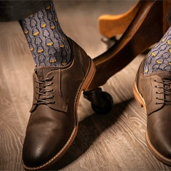 Brown leather shoes with glencairn patterned bourbon socks on a wooden floor