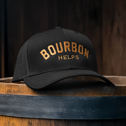 Black cap with 'Bourbon Helps' text on a wooden barrel against a dark background
