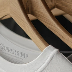 White t-shirt on a wooden hanger with 'Copper & Tap' branding.