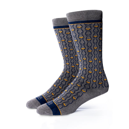Pair of gray bourbon socks with a navy blue whiskey glass pattern on a white background