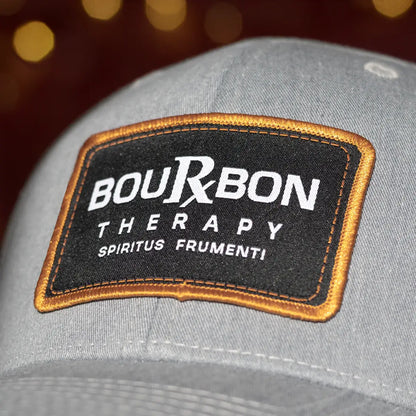 Gray cap with a Bourbon Therapy patch on a blurred background