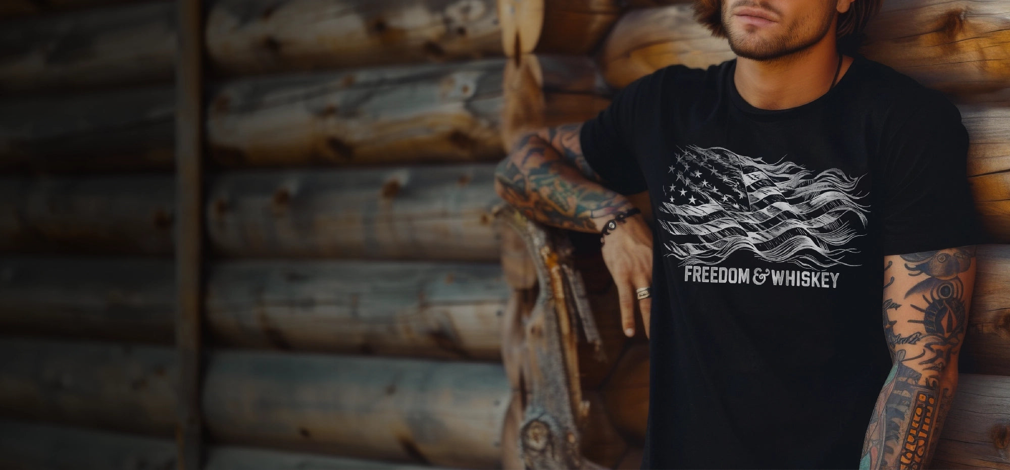 Man wearing a black t-shirt with 'Freedom & Whiskey' design against a wooden wall.
