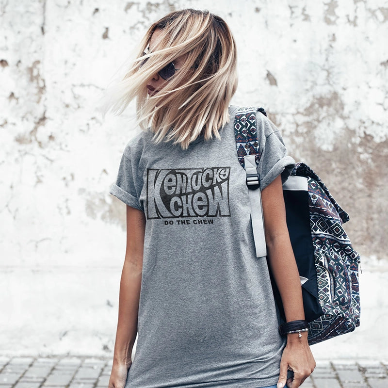 Person wearing a gray t-shirt with 'Kentucky Chew' text, holding a patterned bag.
