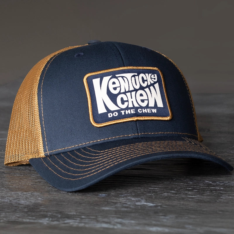 Navy and Caramel Richardson trucker hat with 'Kentucky Chew' logo on a dark surface.
