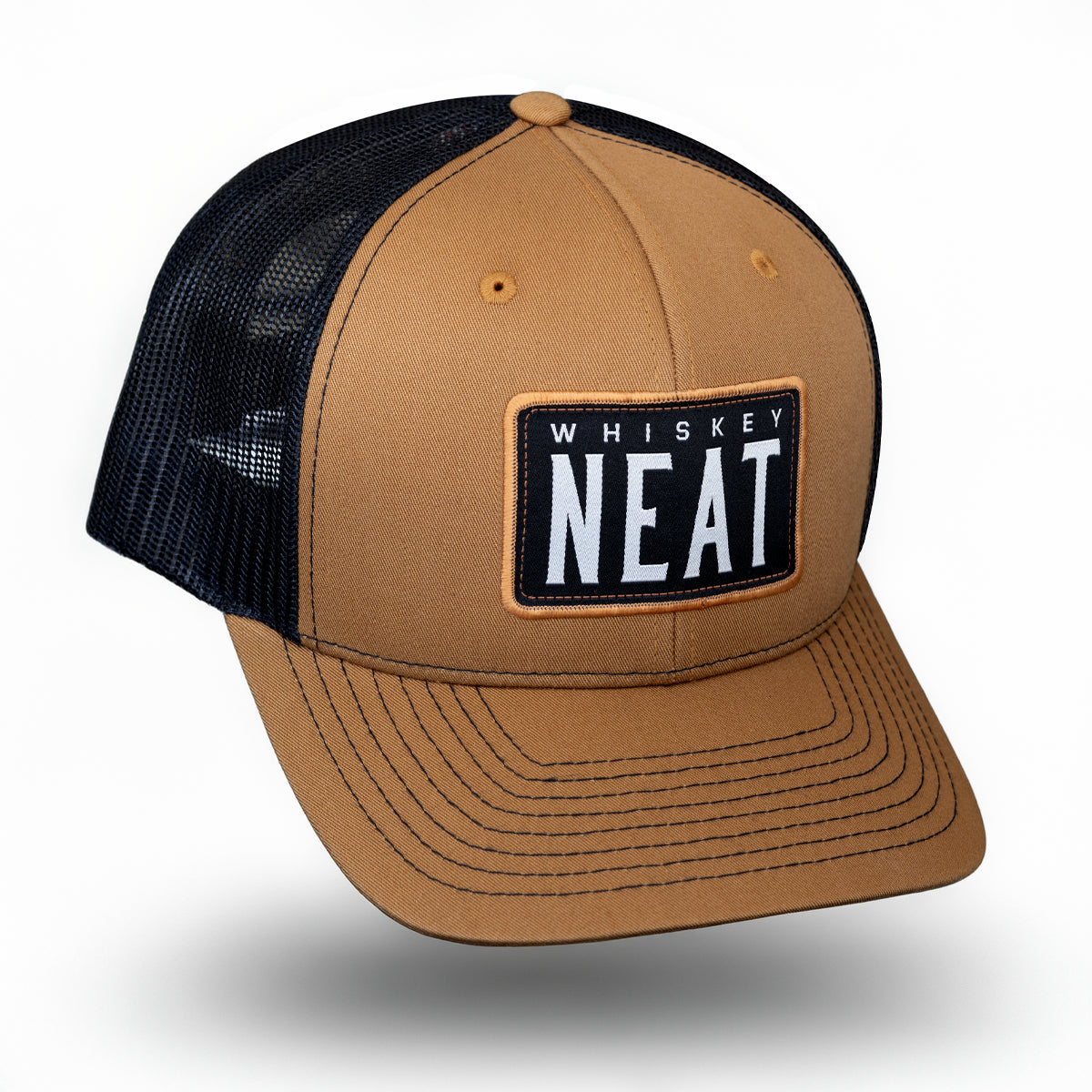 A caramel and black richardson 112 trucker hat with a black mesh back and a front patch reading 'WHISKEY NEAT'.