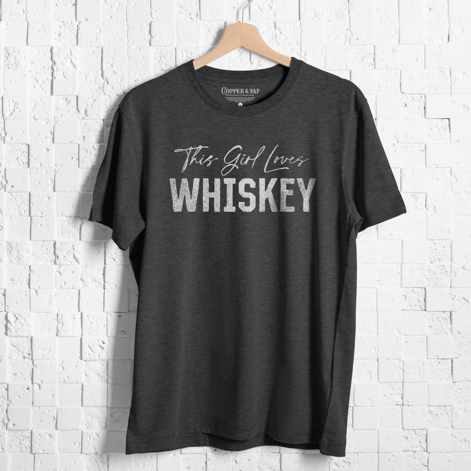 black tri-blend this girl loves whiskey t-shirt hanging against a brick wall