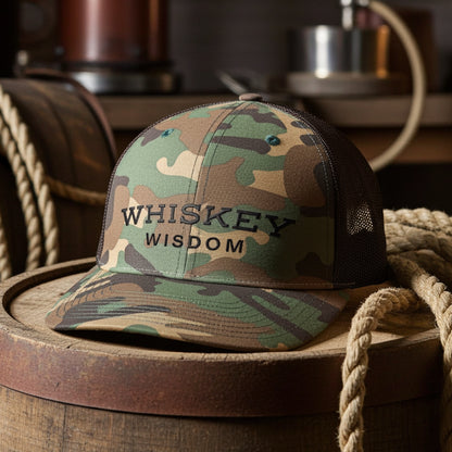 whiskey wisdom camo hat sitting on a wooden barrel
