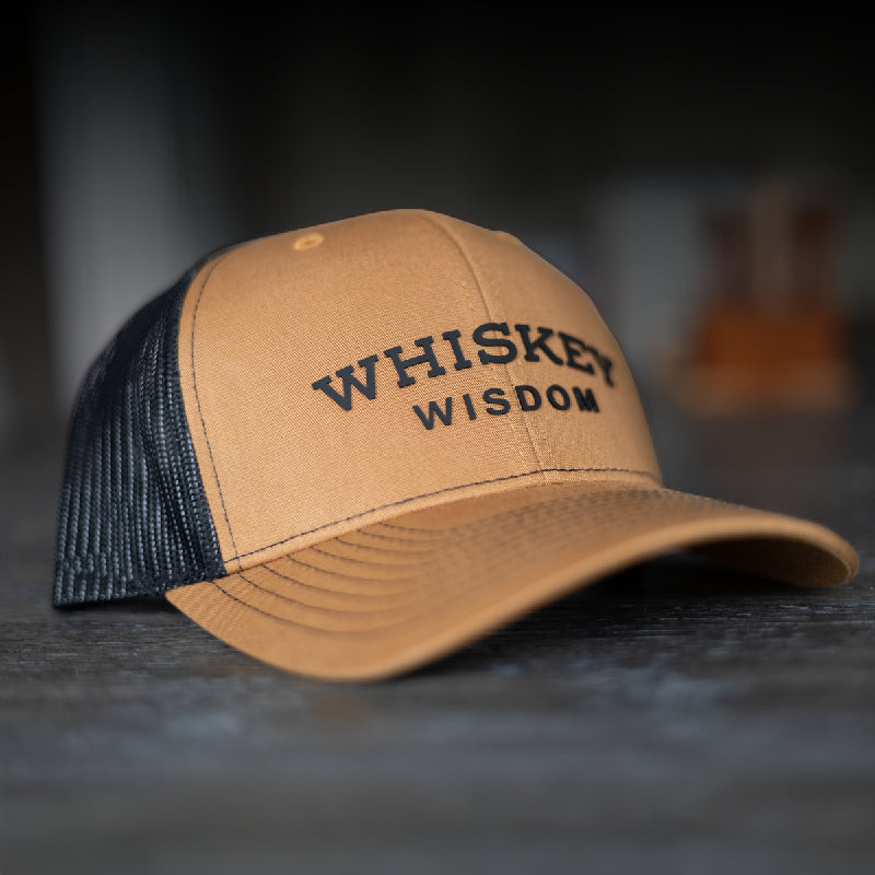 whiskey wisdom richardson 112 caramel and black hat sitting on a wooden surface